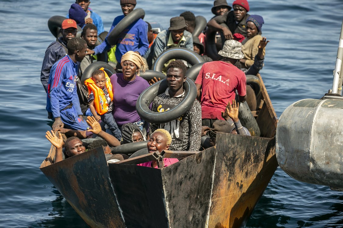 Irregular migrants wearing buoys around their necks are seen in boat.